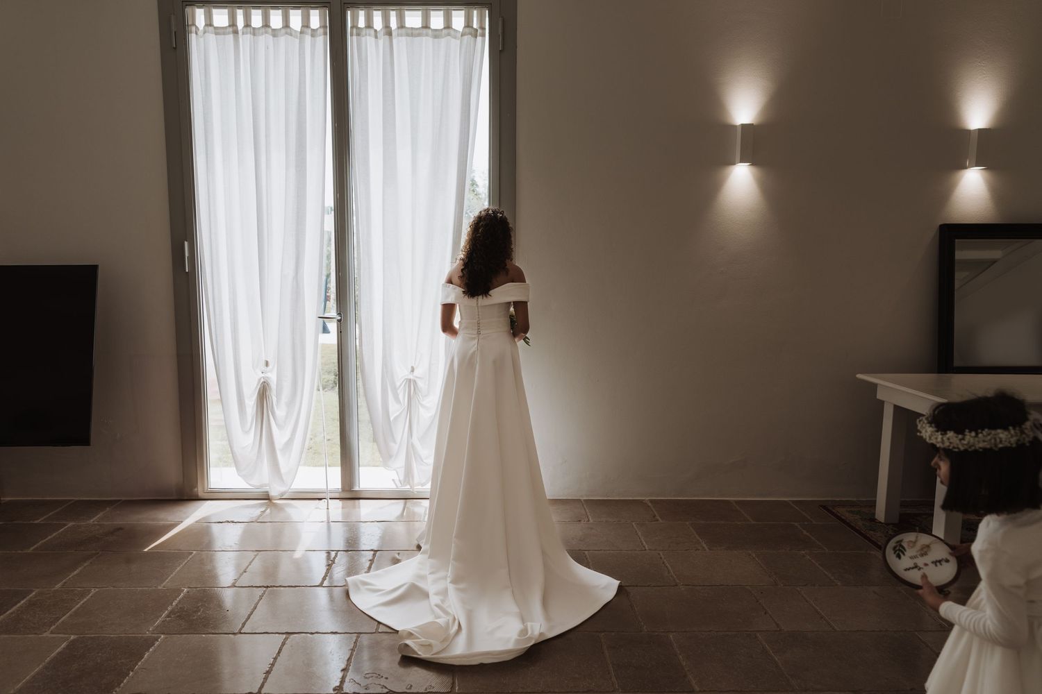 Elegant wedding dress silhouette against French doors in a minimalist room.