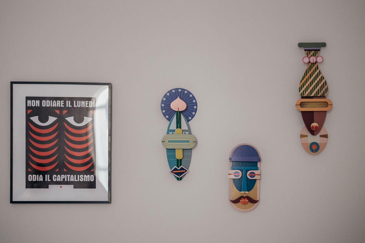Wall display featuring framed poster and decorative face masks in colorful designs.
