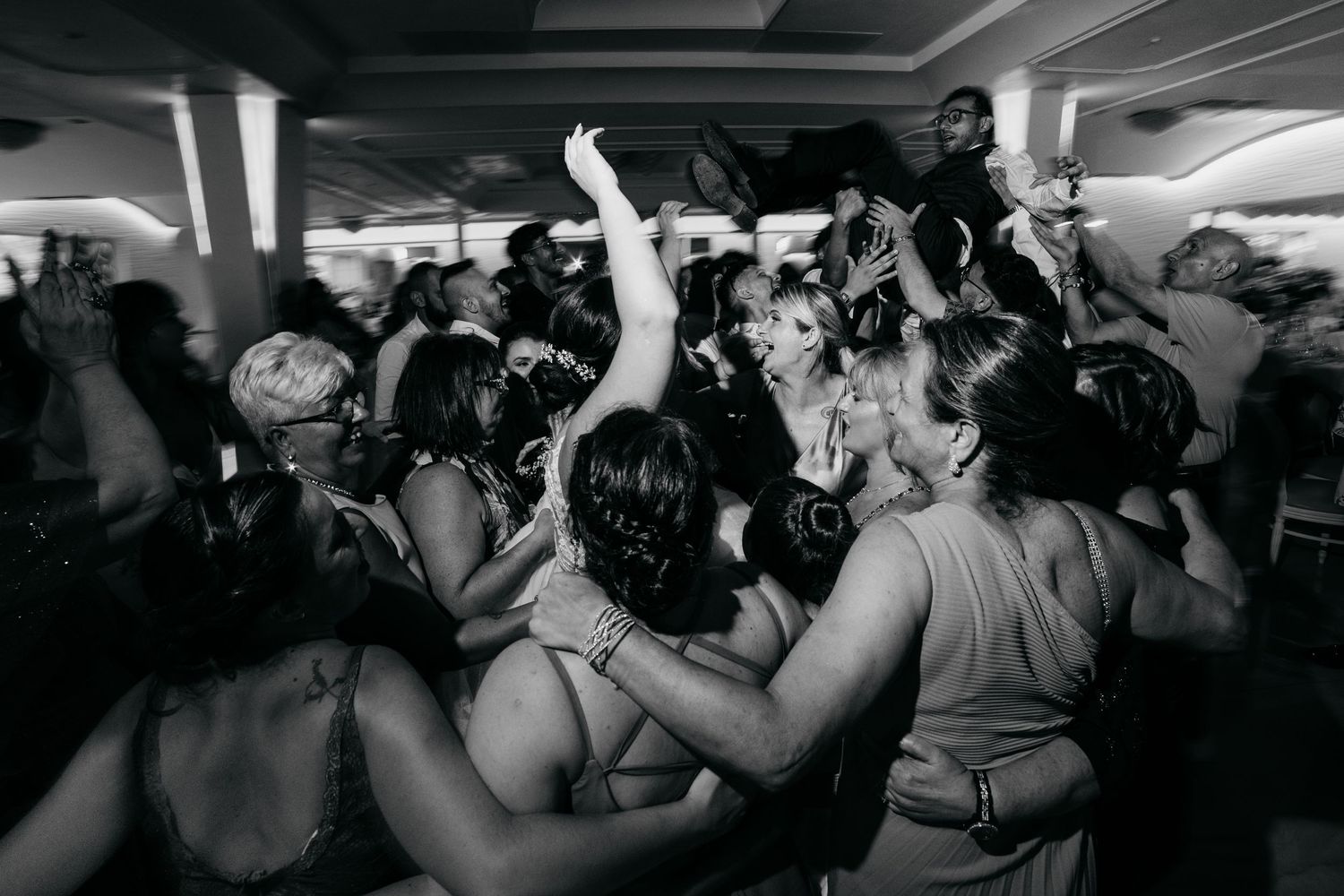 Black and white photo of energetic dancing at a wedding reception.