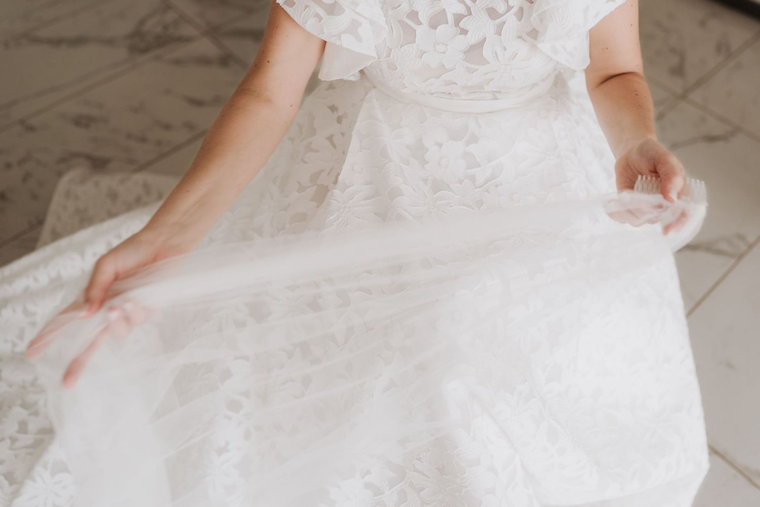 Detail shot of a white lace wedding dress with intricate patterns.