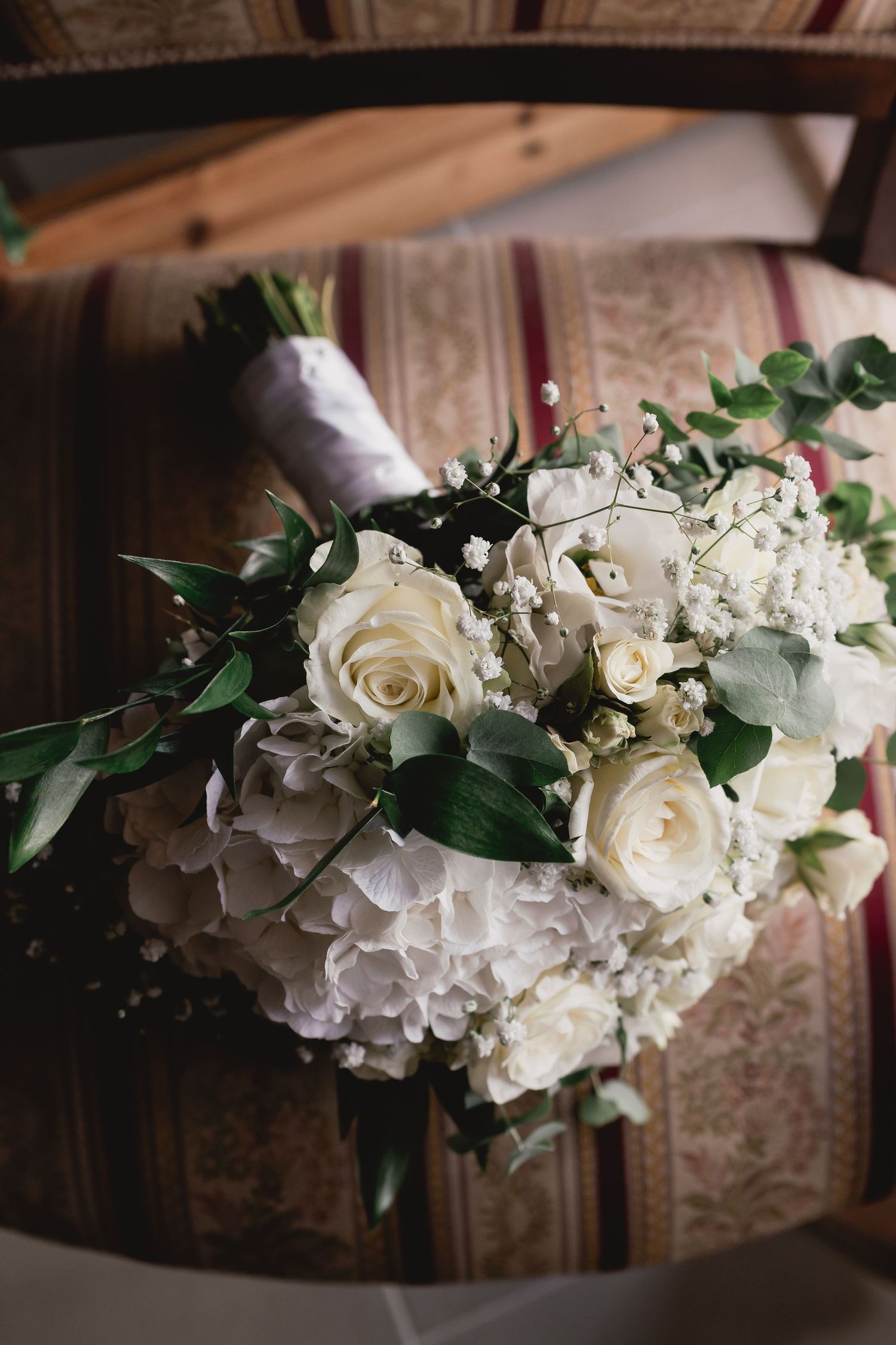 Elegant white wedding bouquet with roses, hydrangeas and eucalyptus leaves.