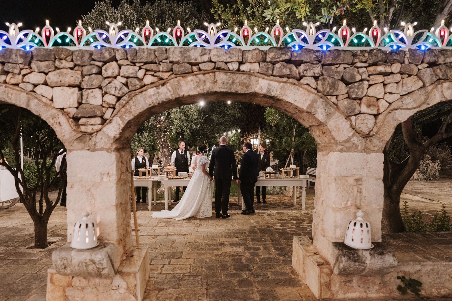 Stone archway decorated with twinkling lights at an outdoor wedding venue.