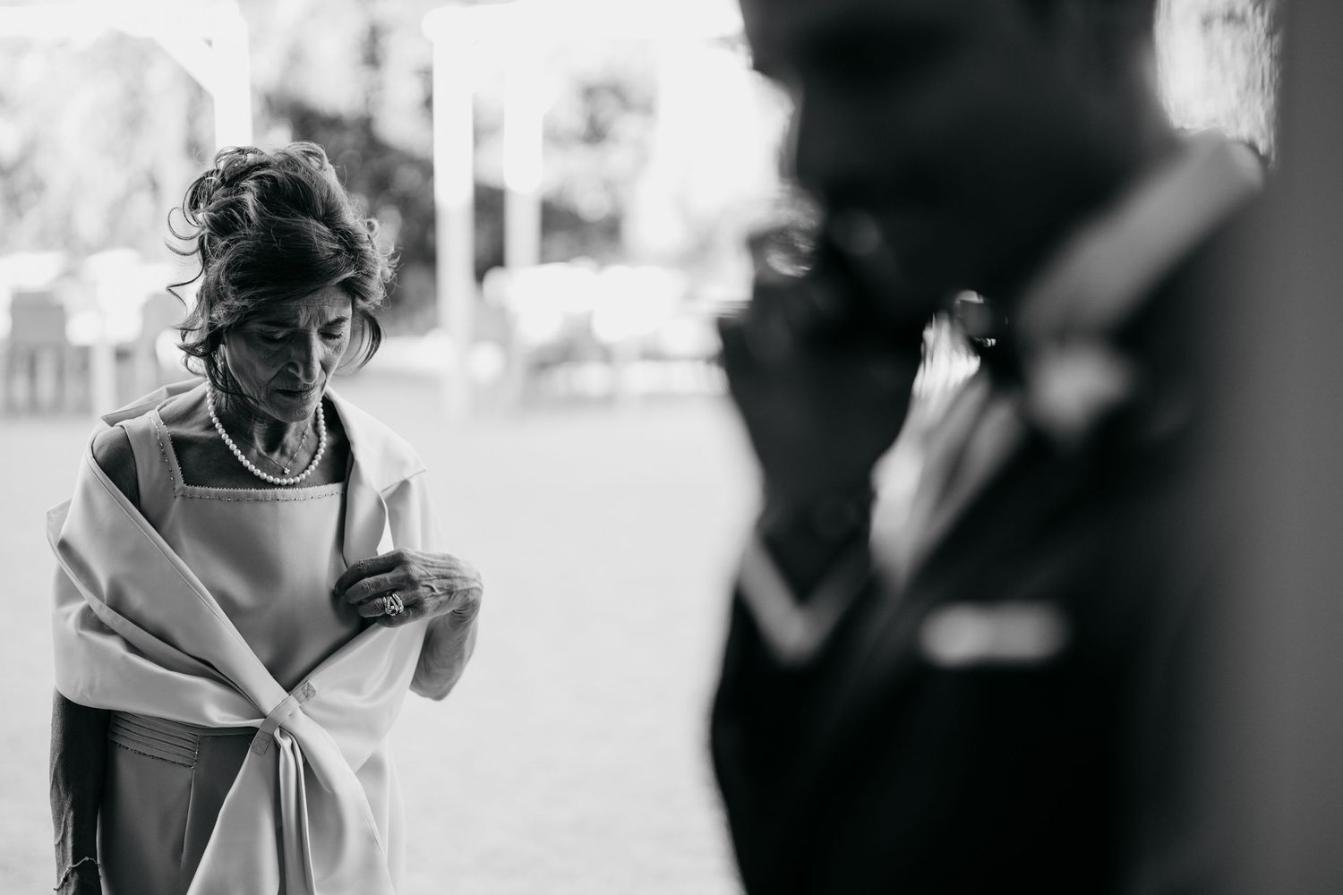 Artistic black and white candid photograph capturing intimate wedding moment outdoors.