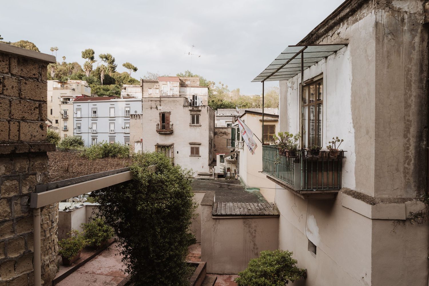 Rustic Italian hillside neighborhood with white buildings and traditional balconies on a cloudy day.