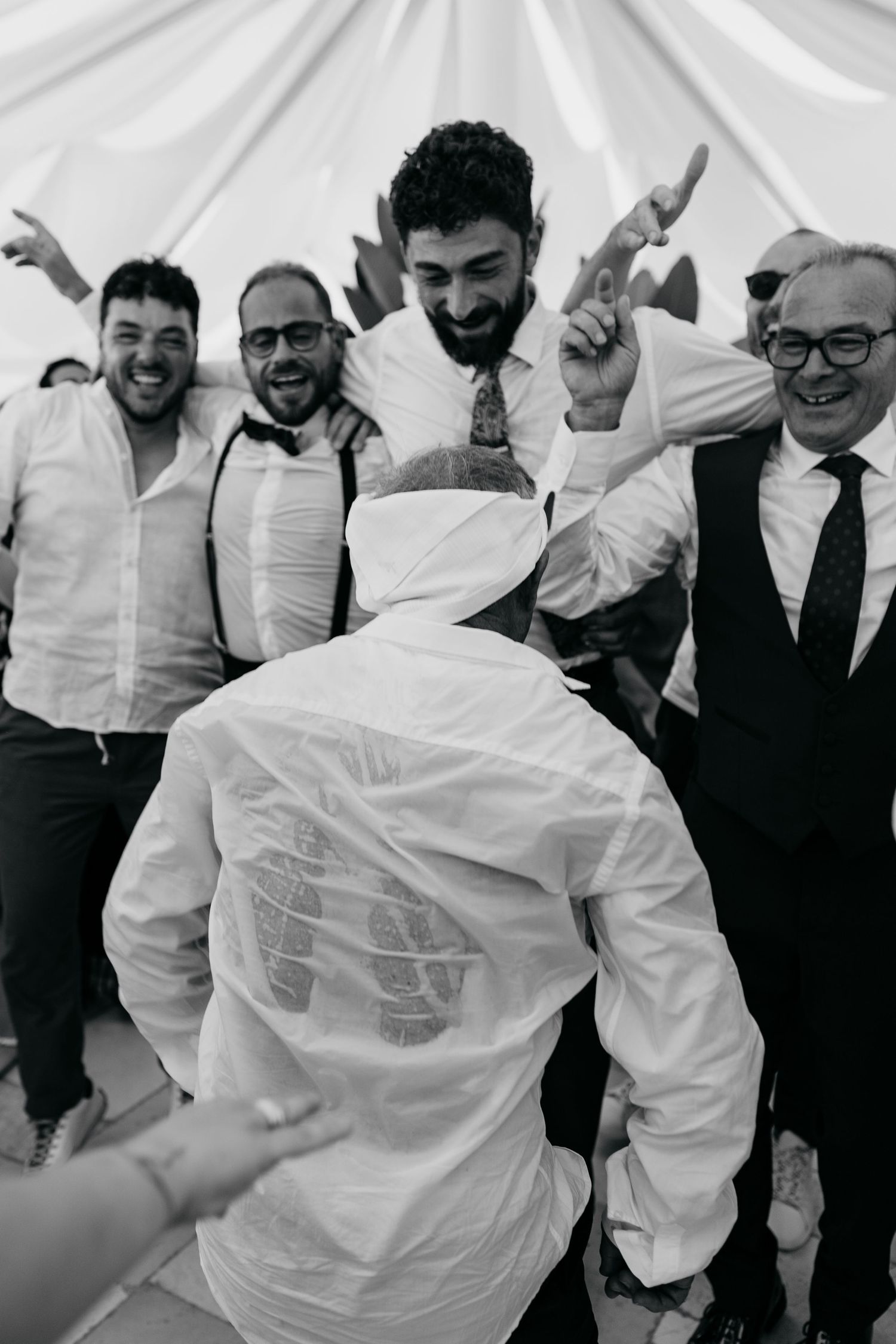 Black and white candid photo of wedding guests celebrating and dancing.