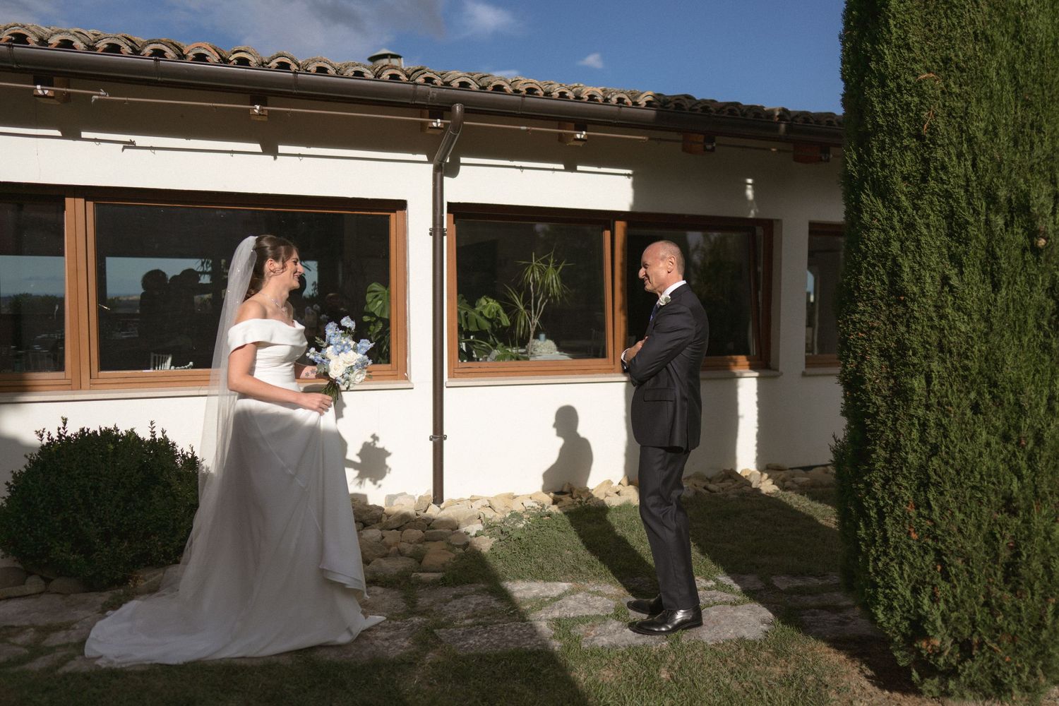 Exterior view of a Mediterranean style building with white walls and cypress trees.