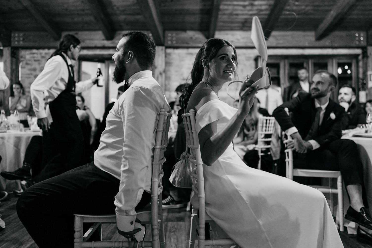 Wedding guests dancing and celebrating in a dimly lit reception venue.
