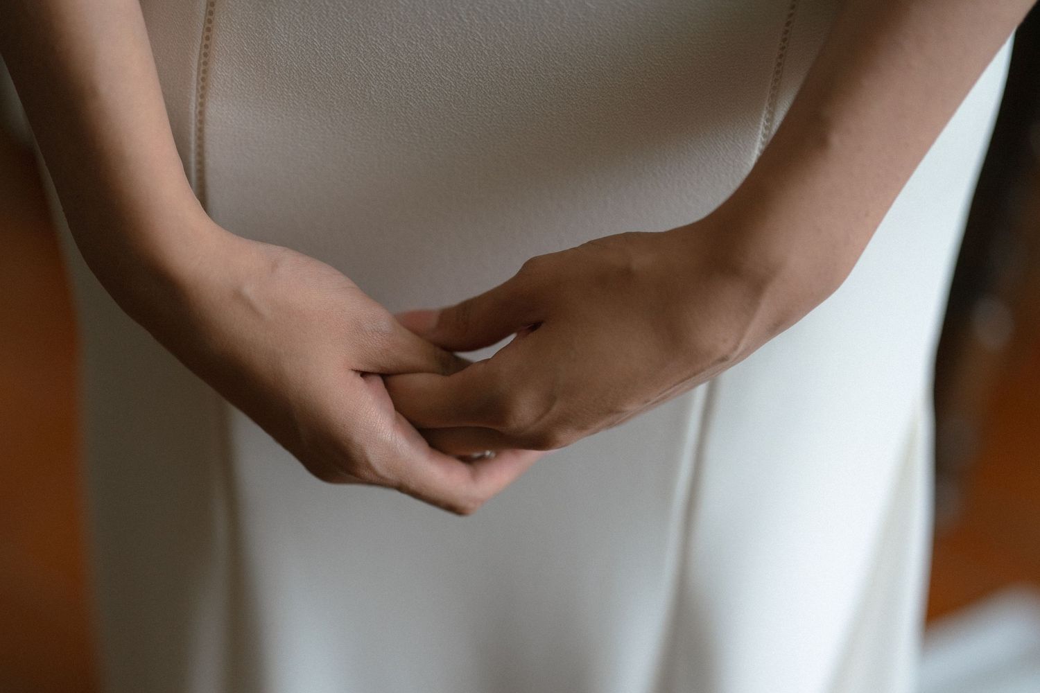 Close-up view of hands holding a white ceramic mug against a blurred background.