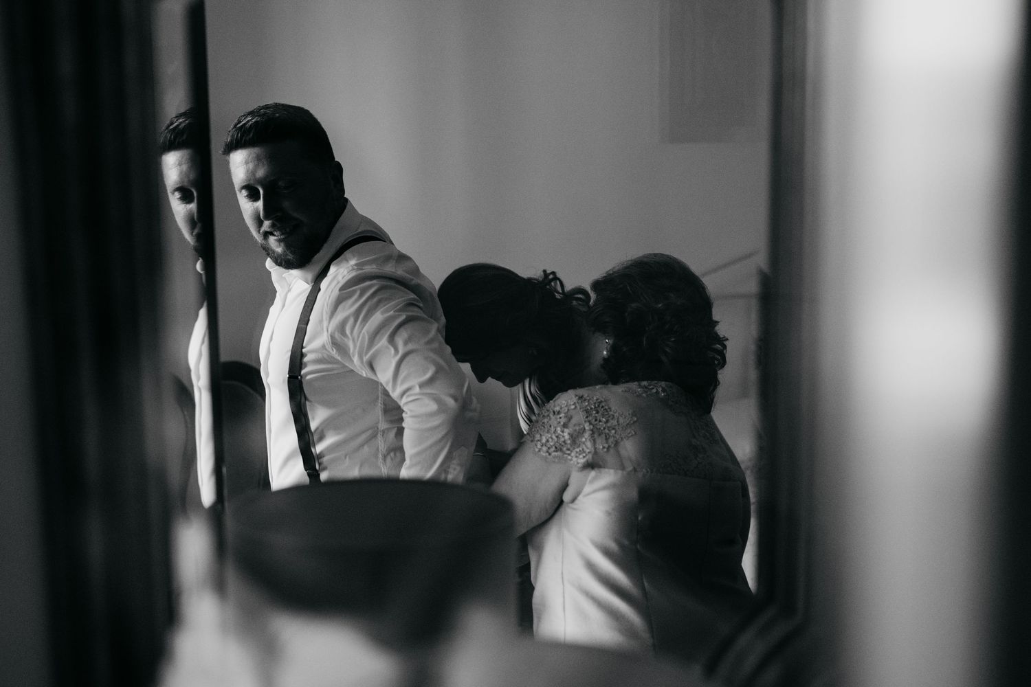 Black and white photo showing people getting ready in a room with dramatic lighting and shadows.
