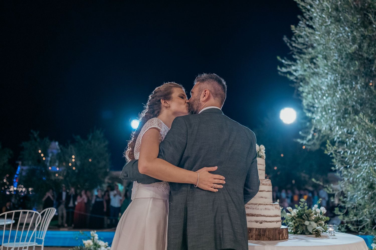 Romantic outdoor evening dance moment captured under moonlit sky at wedding reception.