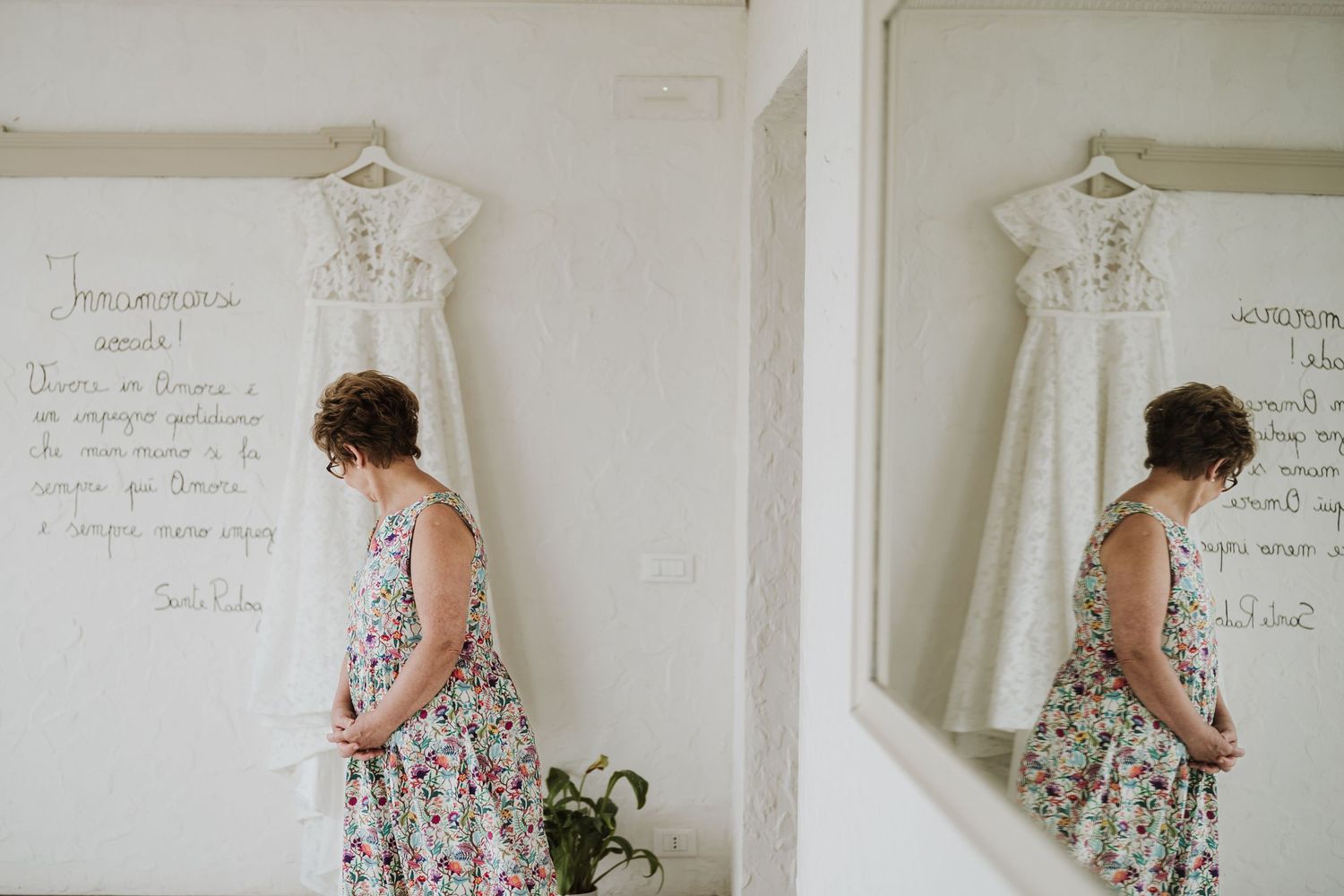 Wedding dress hanging on wall with handwritten text and mirror reflection.