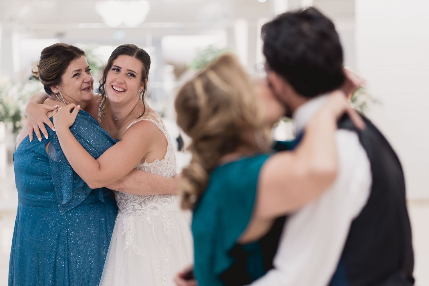Emotional embrace during a wedding celebration with guests watching in the background.