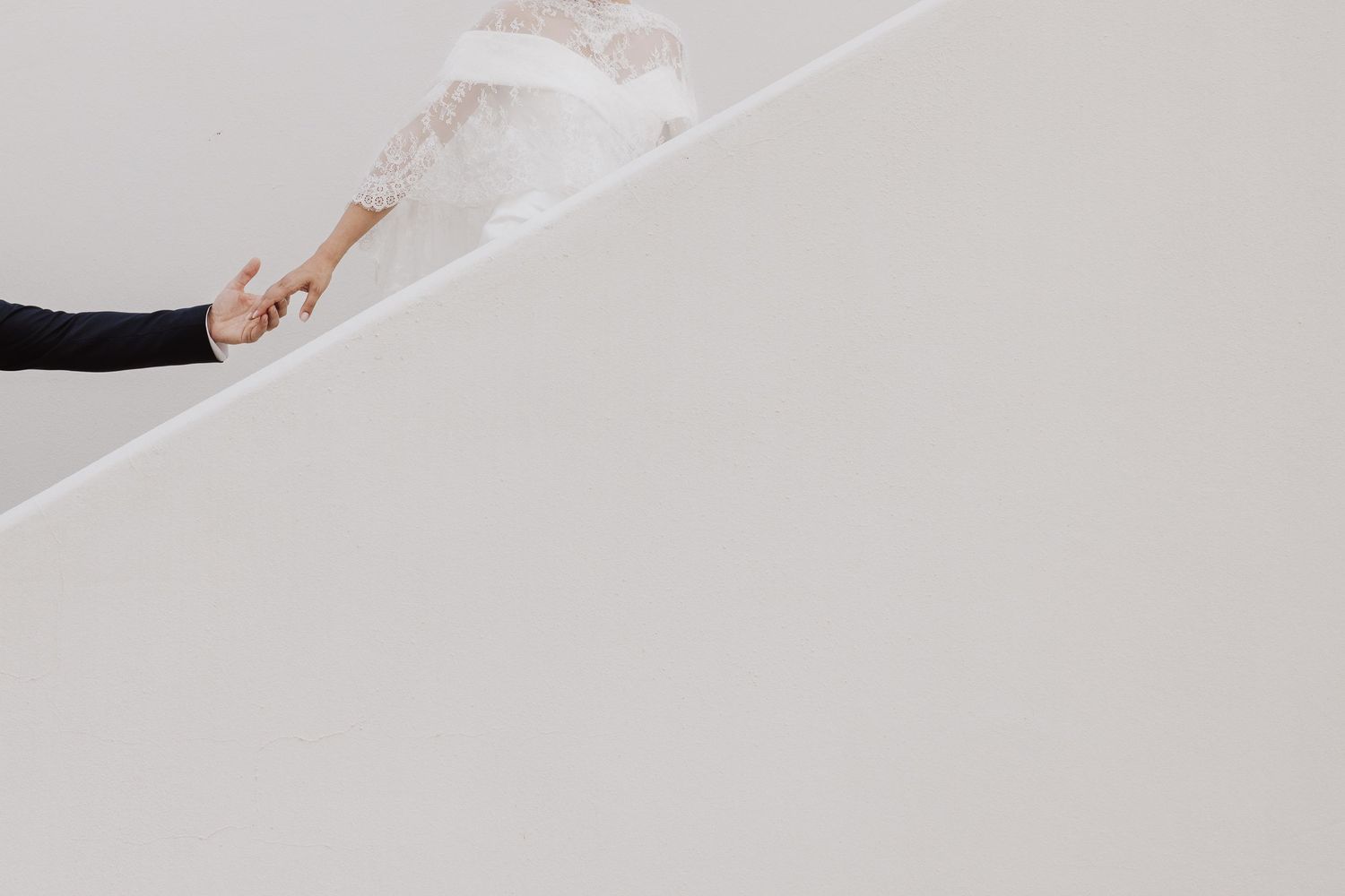 Hand holding a white string or rope against a light gray background in minimalist composition.