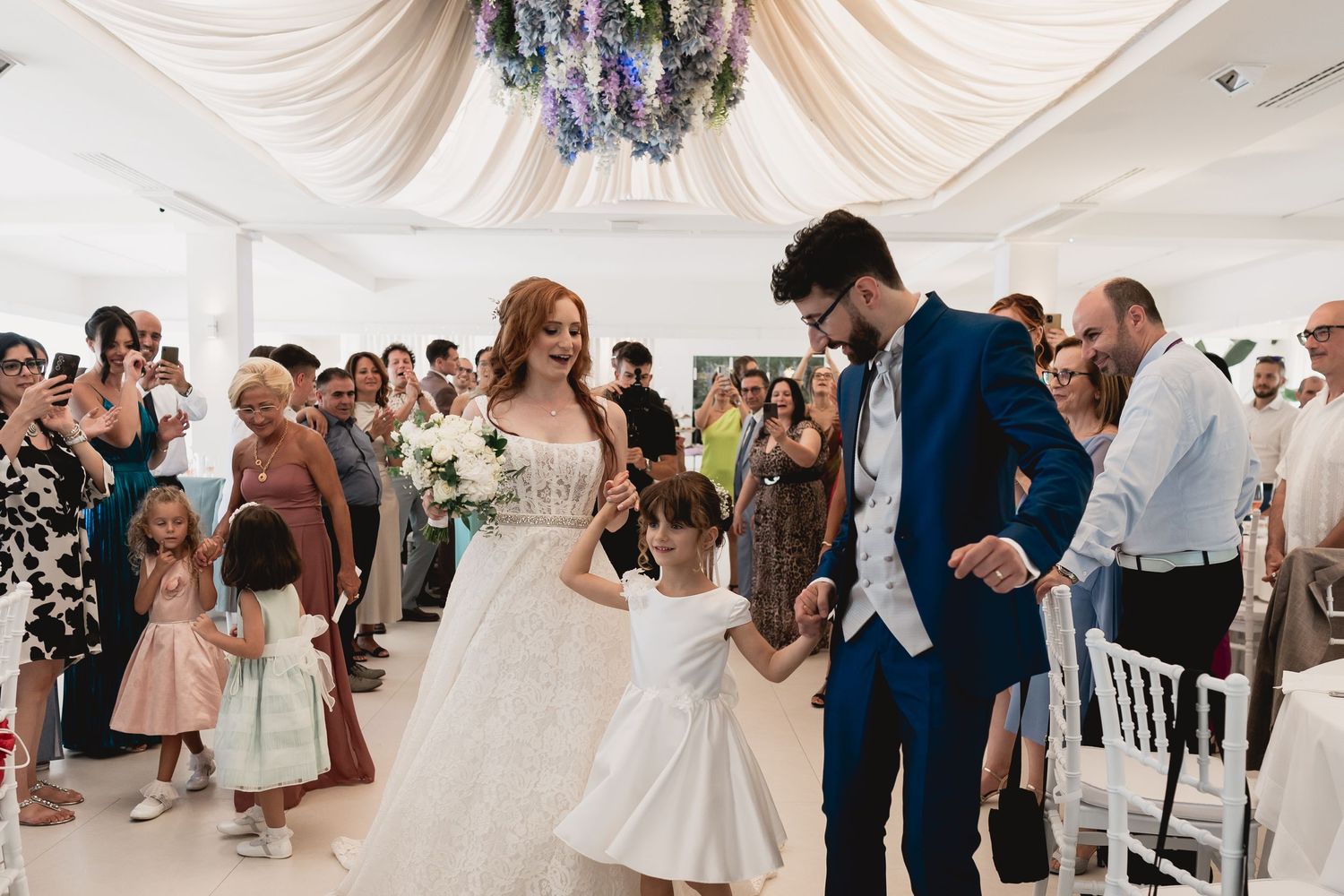 Wedding celebration with guests dancing in an elegantly decorated white tent venue.