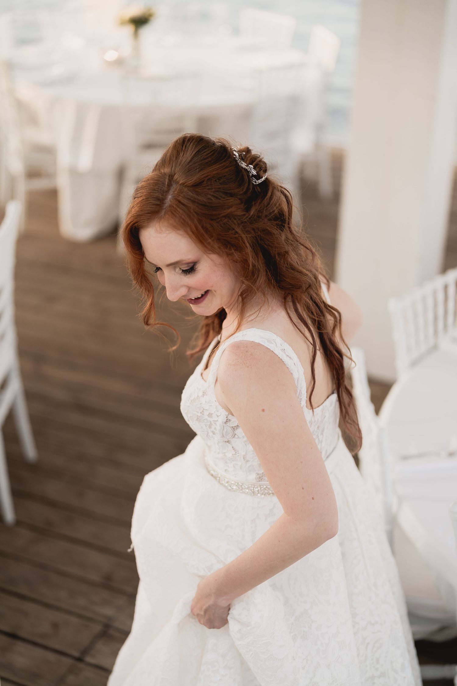 Candid moment of a bride in a white lace dress laughing during her wedding day.