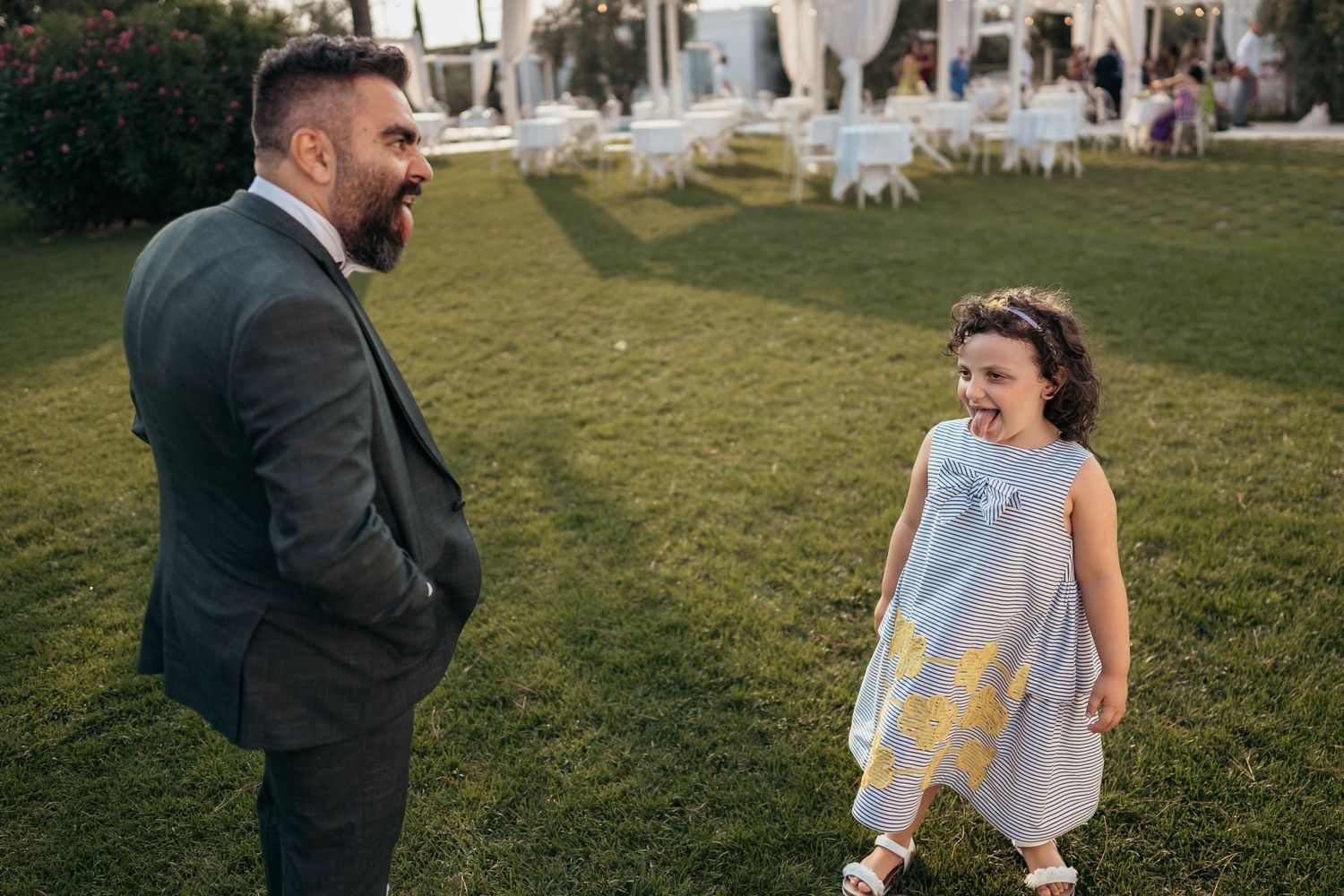 Candid moment of laughter shared on a grassy lawn during a wedding celebration.