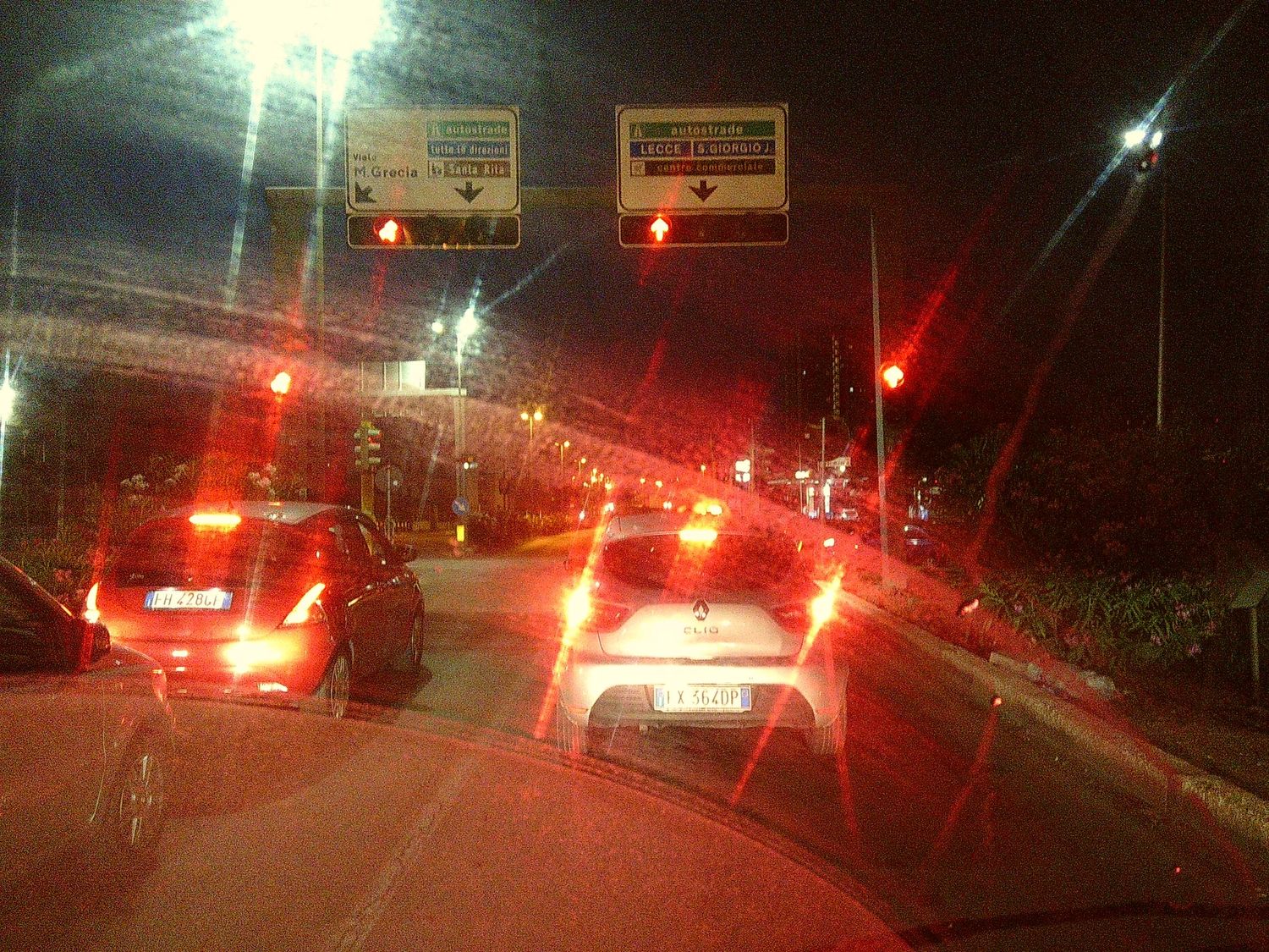 Traffic jam at night with red brake lights glowing on a busy street.