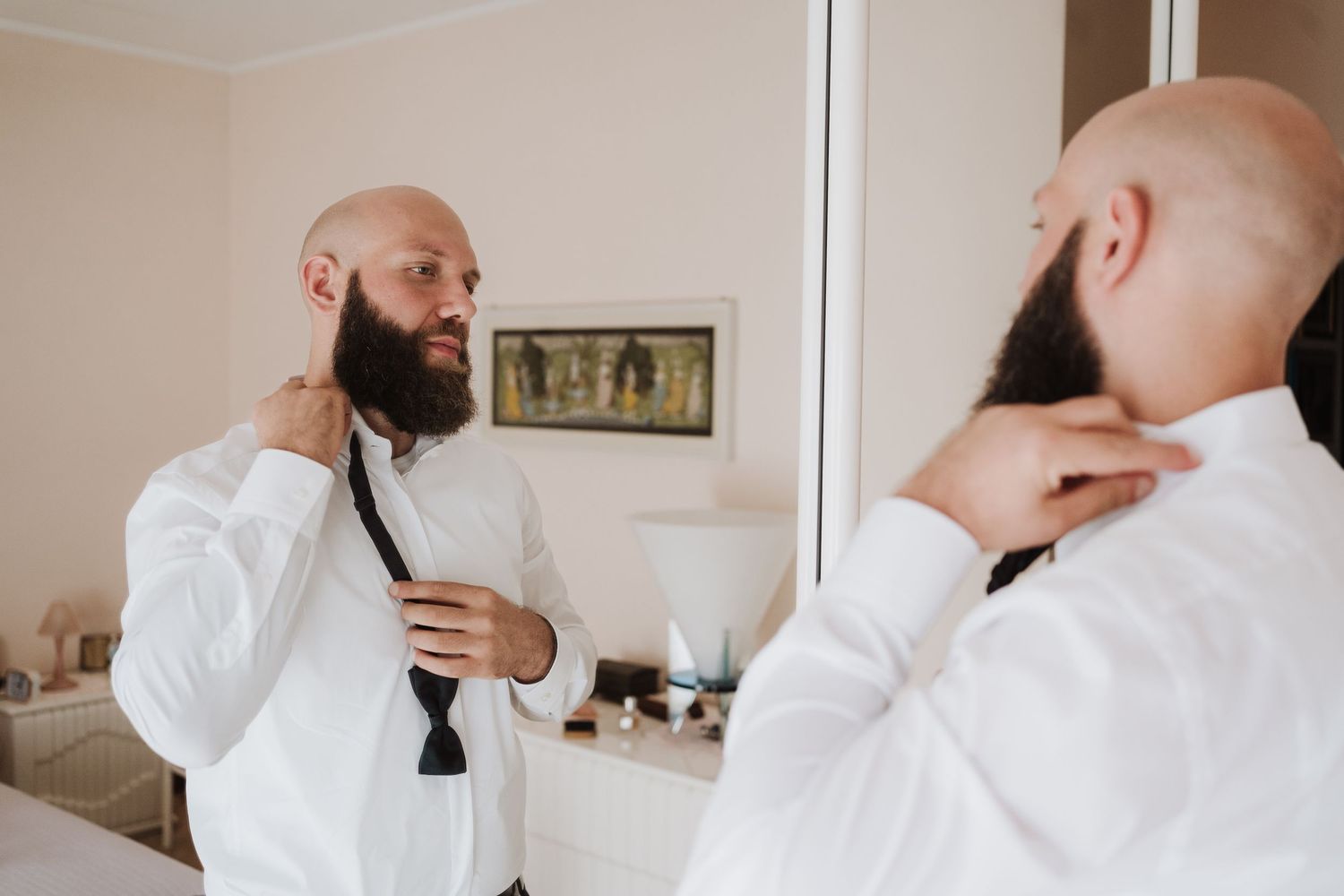 Getting ready reflection in mirror while adjusting bow tie.