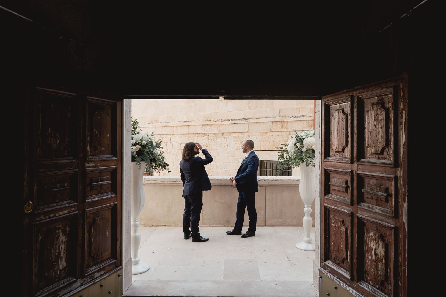 Two figures silhouetted in conversation through ornate wooden doorway.