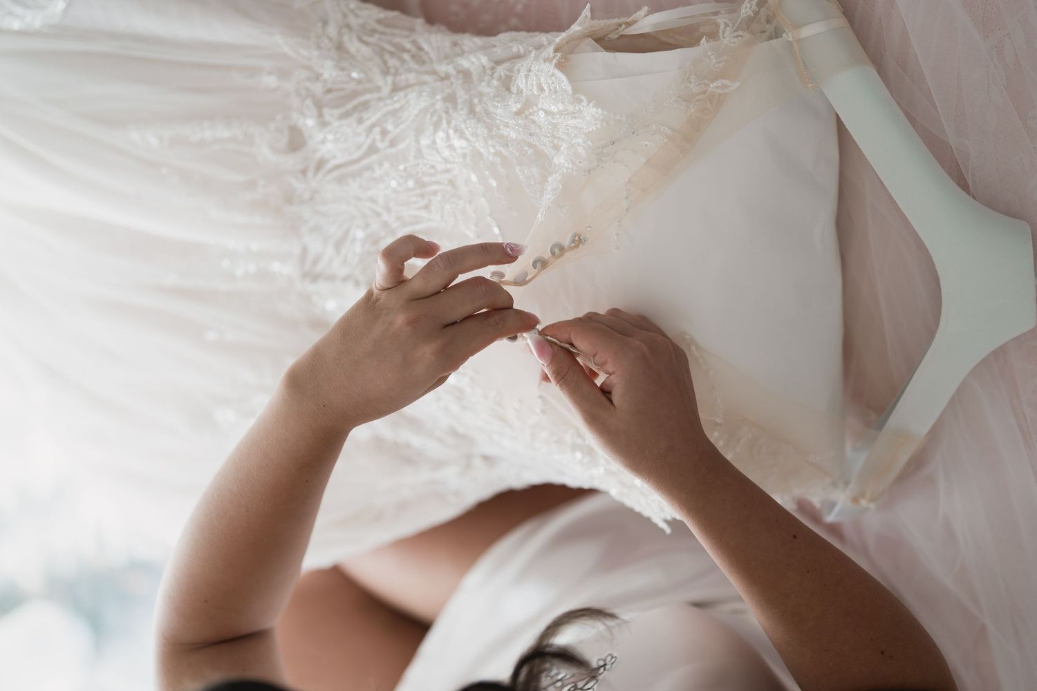 Close up of hands working with delicate white fabric details.