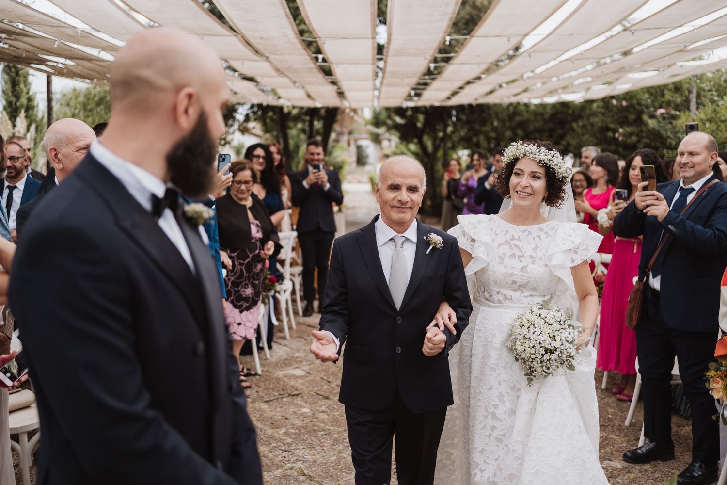 Wedding ceremony processional under string lights with guests seated along pathway.