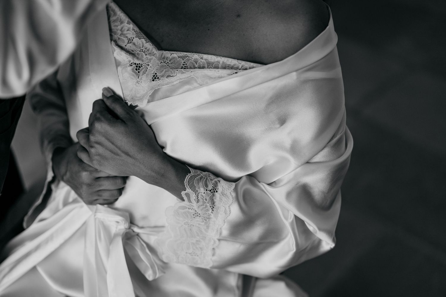 Close-up detail of delicate lace on a white wedding dress fabric.