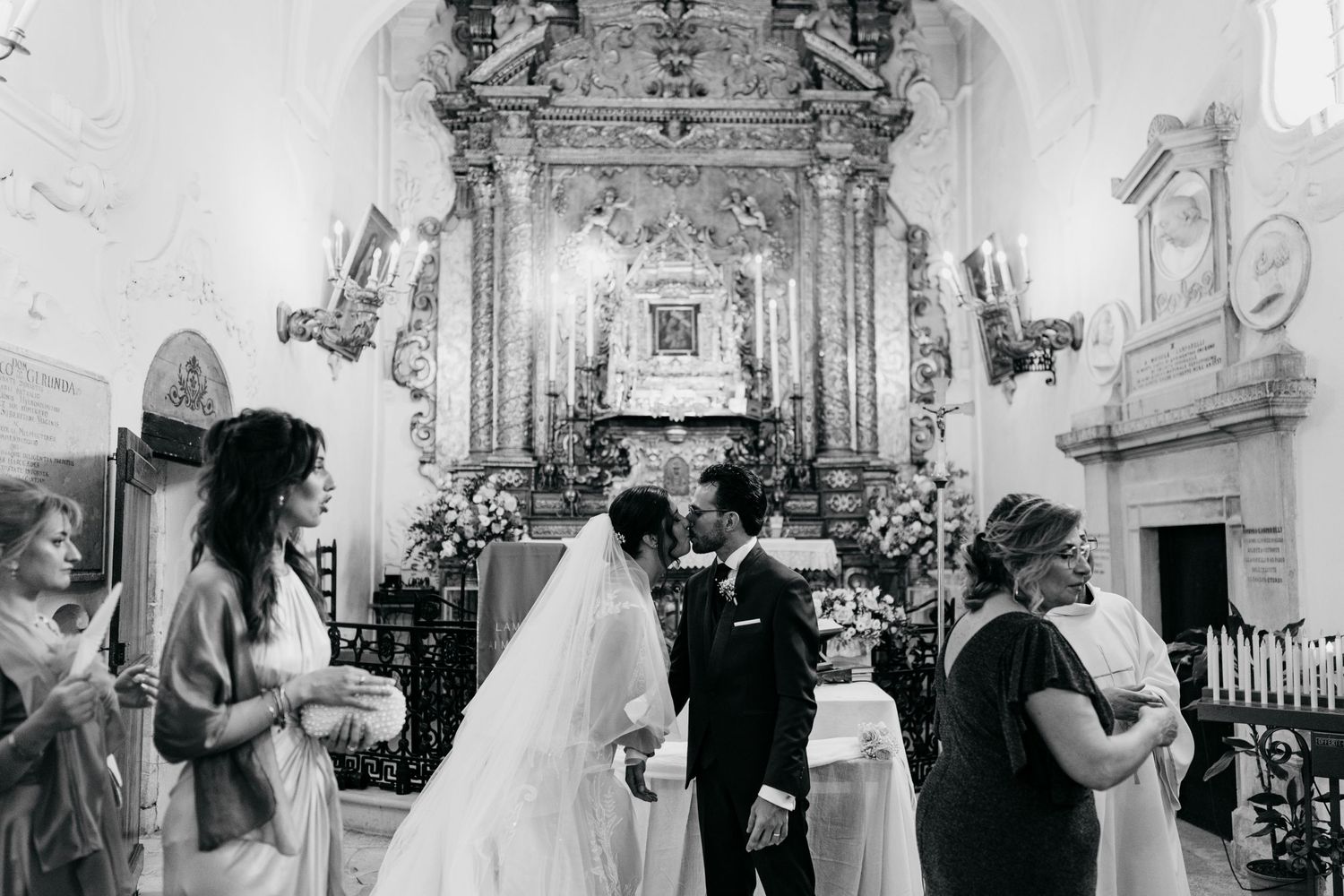 A black and white photograph of a wedding ceremony in front of an elaborate baroque altar.