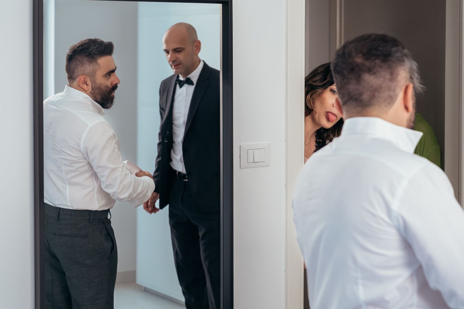 People in formal attire having discussion near mirror.