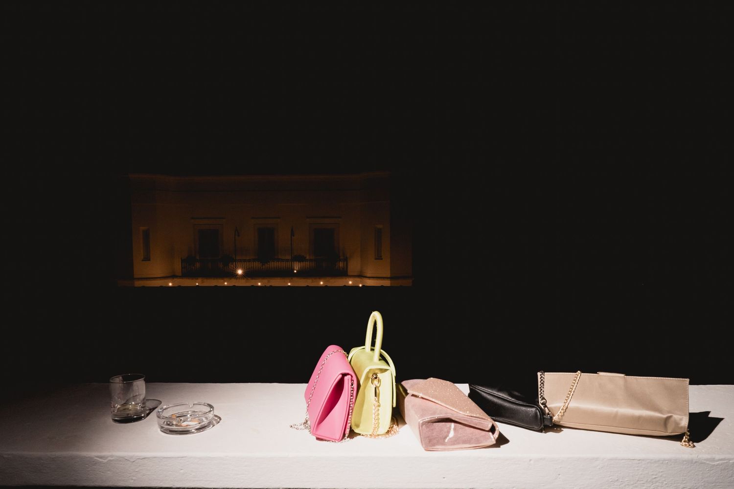 Wedding accessories including shoes and bags arranged on a white surface with dark lighting.