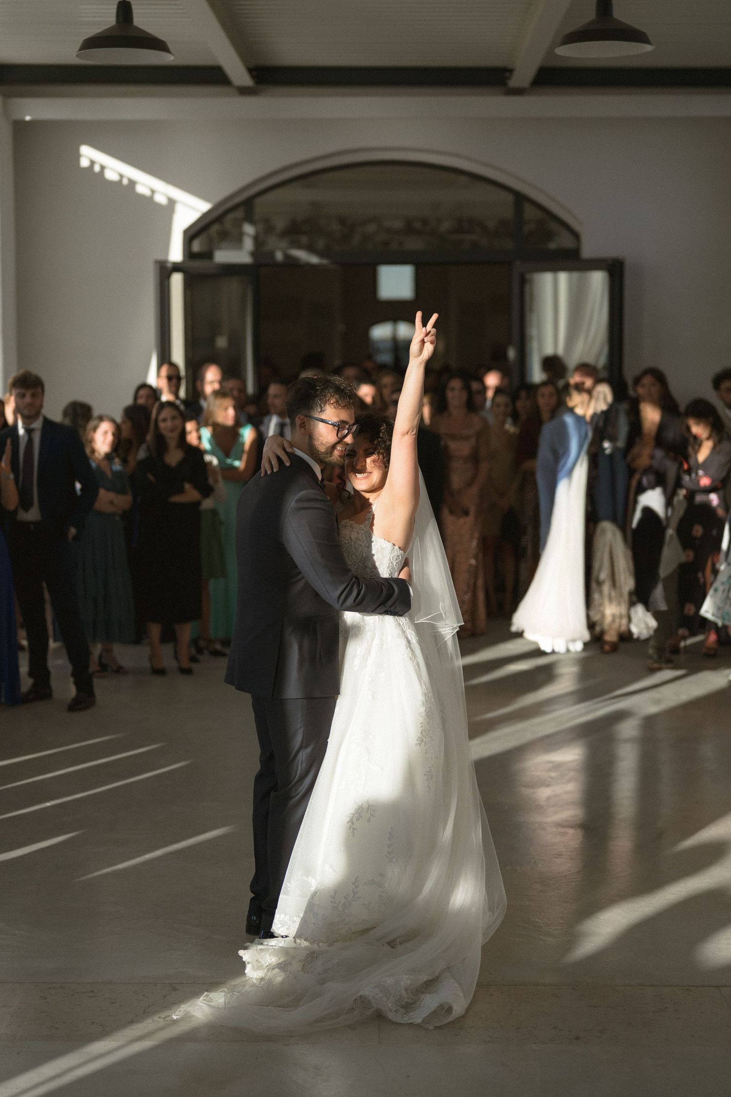 Bride and groom share first dance while bride raises hand at elegant wedding reception.