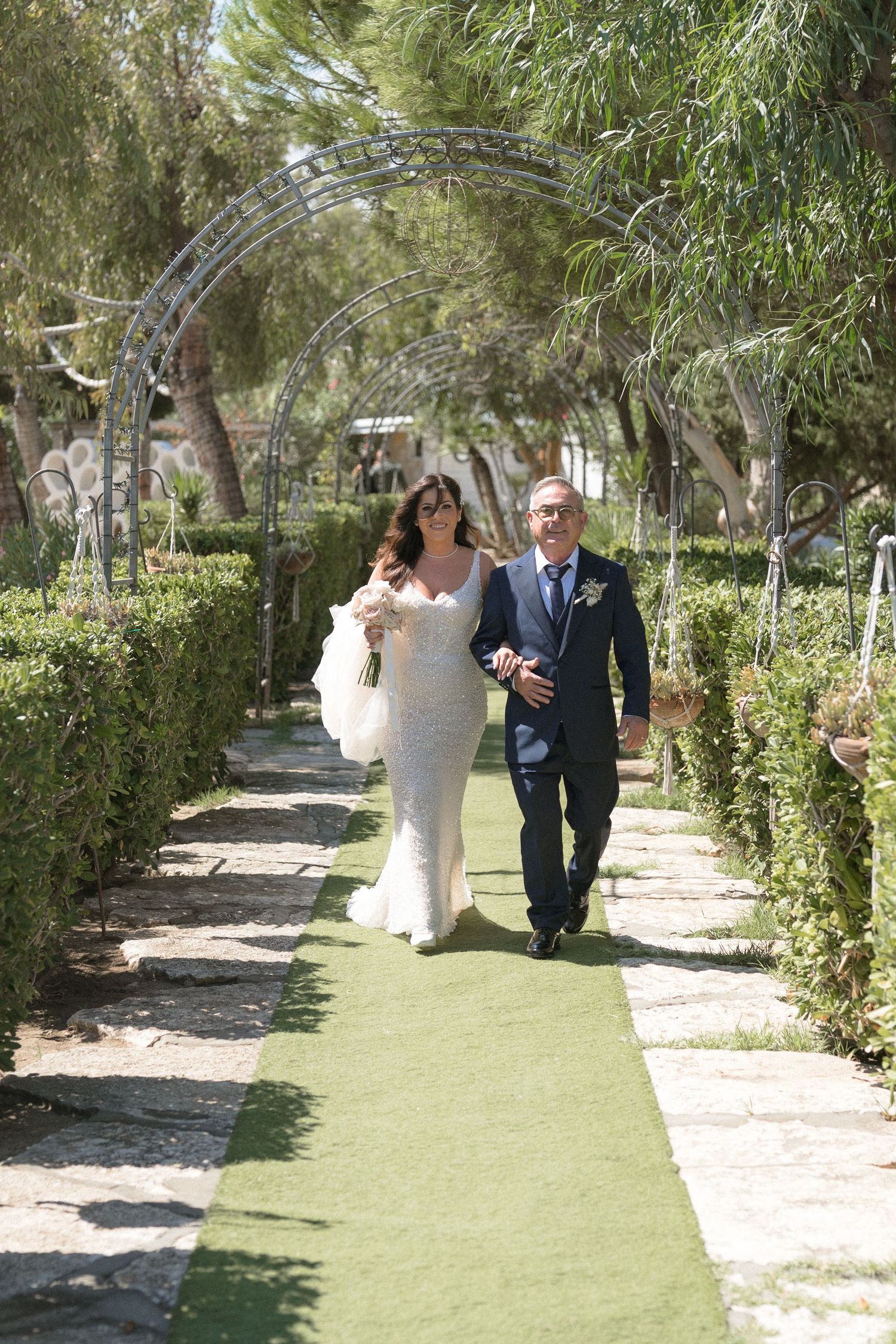 Garden pathway lined with greenery and trees for a wedding ceremony.