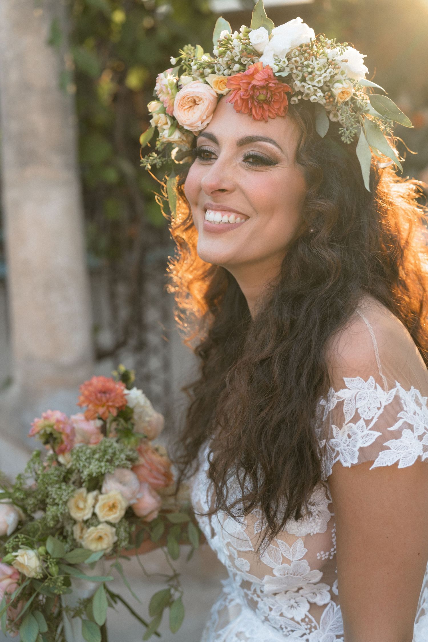 Beautiful lace wedding dress and floral crown details in warm sunset lighting.