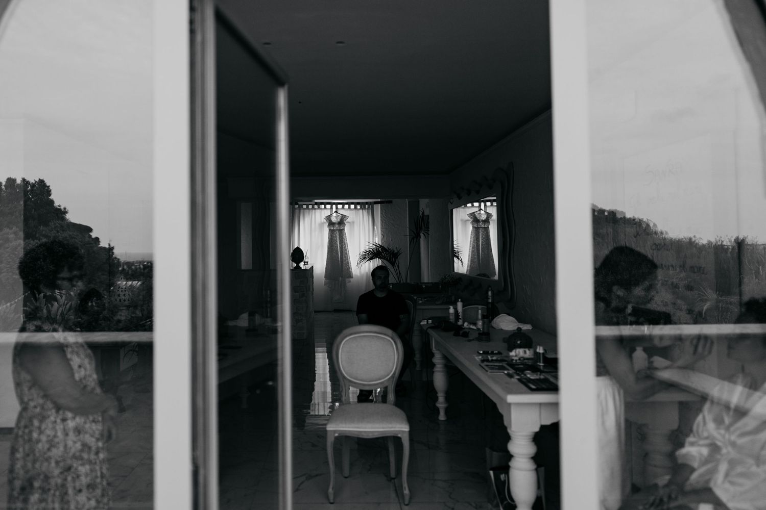 A moody black and white interior hallway view with vintage furniture and curtained windows.