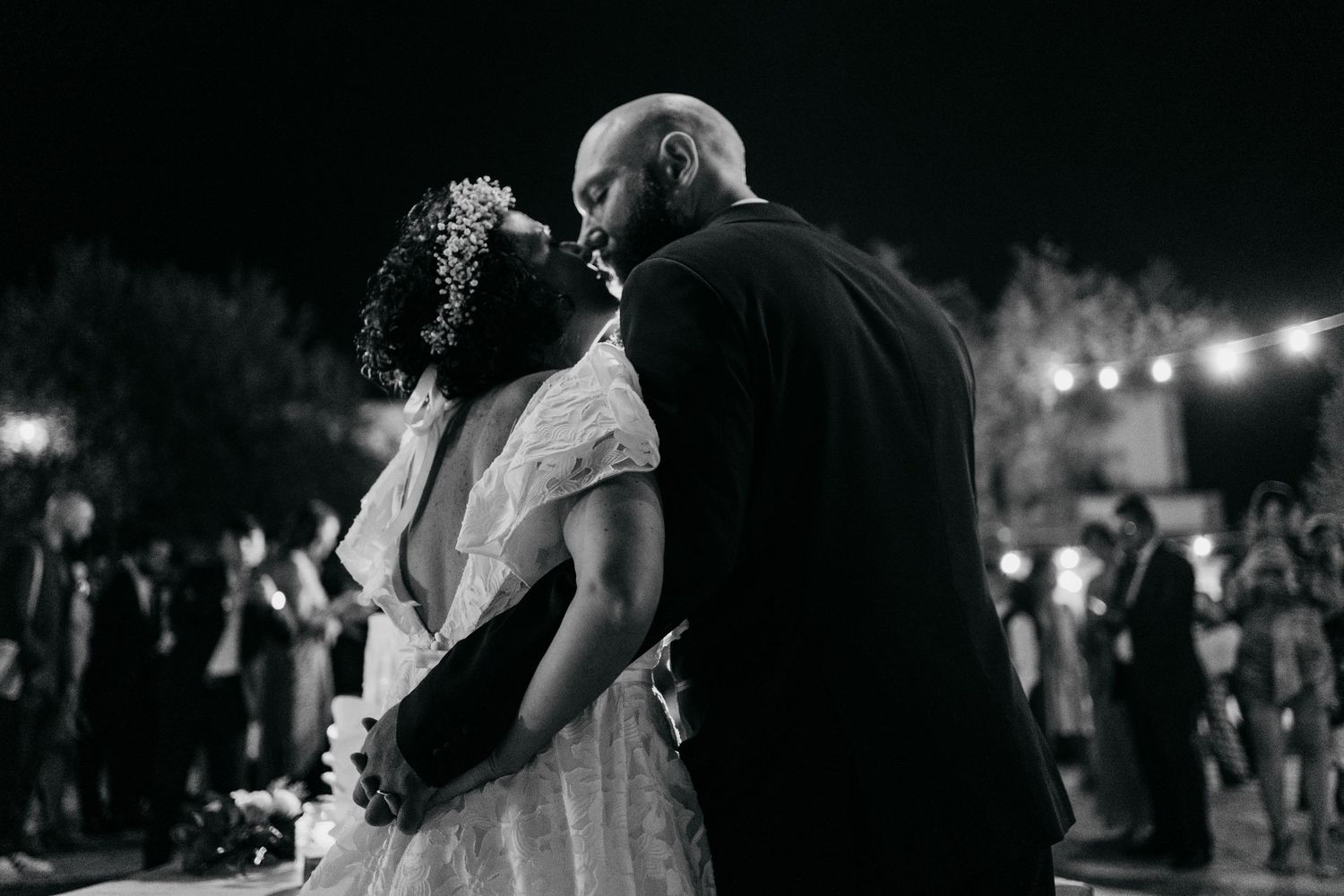 A romantic black and white dance moment at an outdoor evening wedding reception.