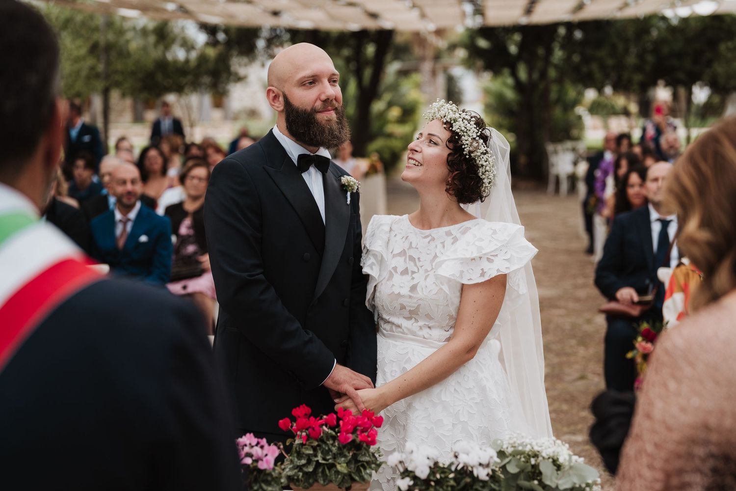 Couple shares a joyful moment during outdoor wedding ceremony with guests seated behind them.