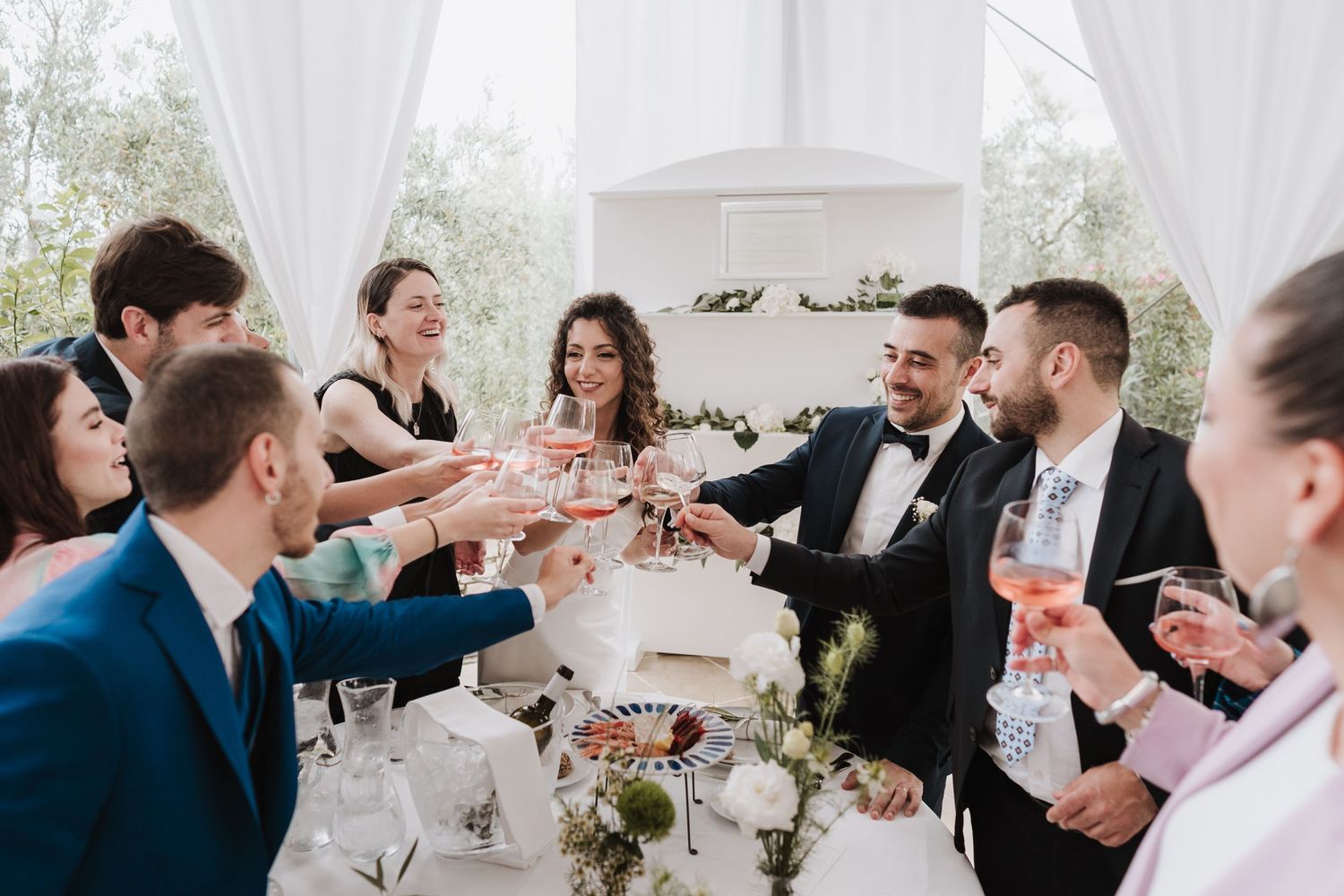 Wedding party raising glasses in a celebratory toast at an elegantly decorated reception table.
