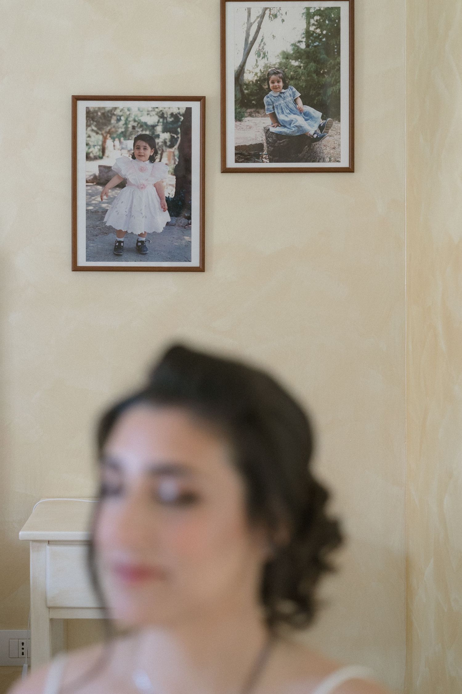 A wall display of vintage framed photographs showing childhood memories and family portraits.