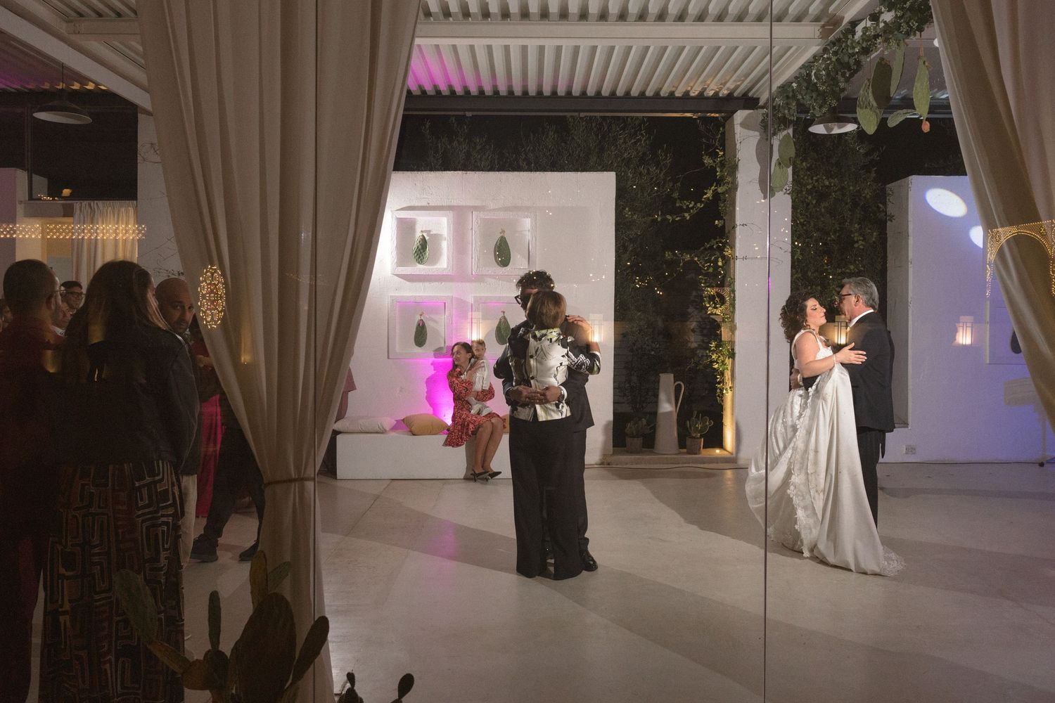 Couple sharing first dance at an elegant indoor wedding reception with ambient lighting.
