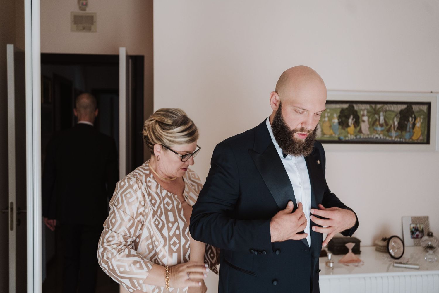 Wedding preparation scene with formal attire adjustments being made.