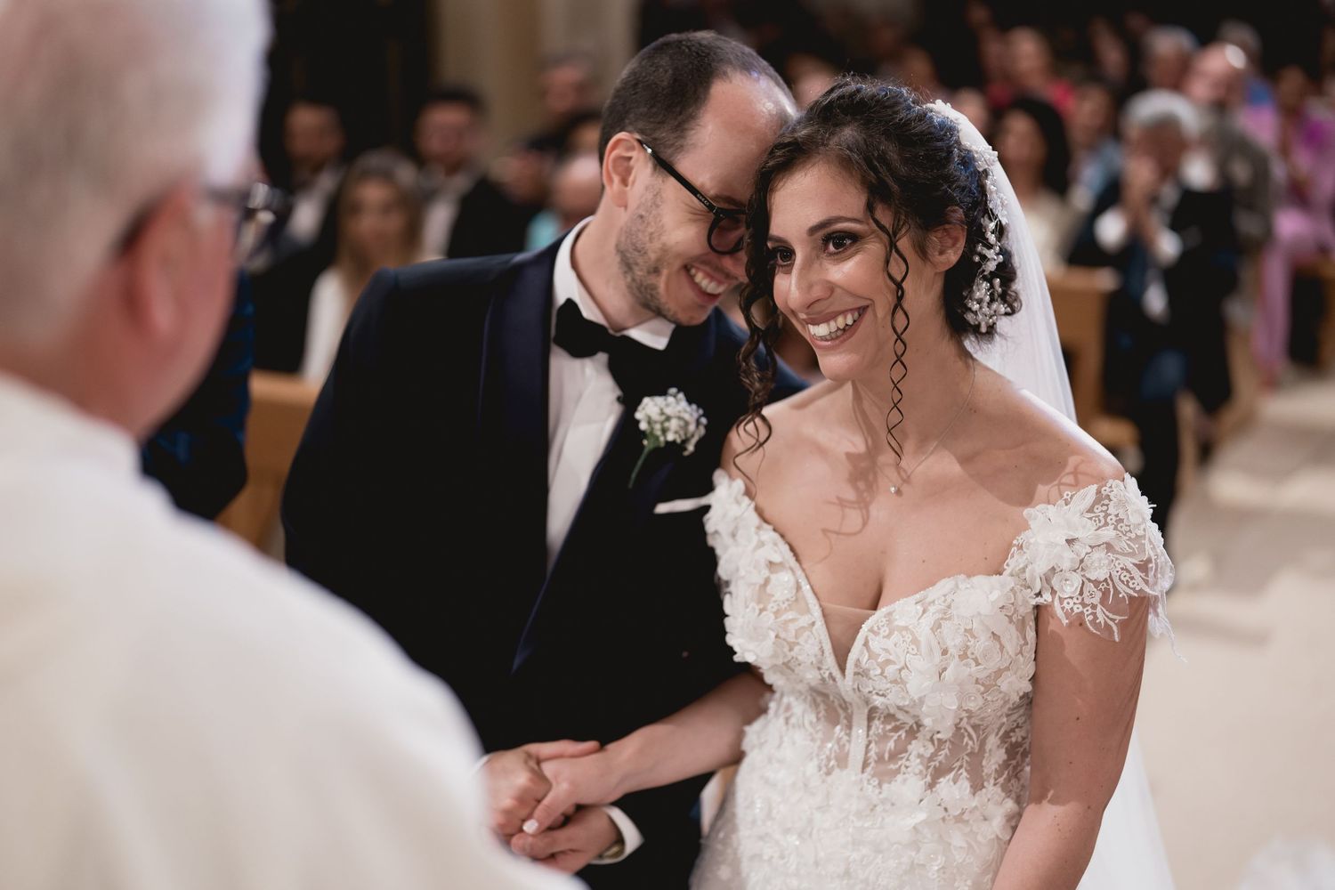 Intimate wedding ceremony moment in an ornate Catholic church with warm lighting.