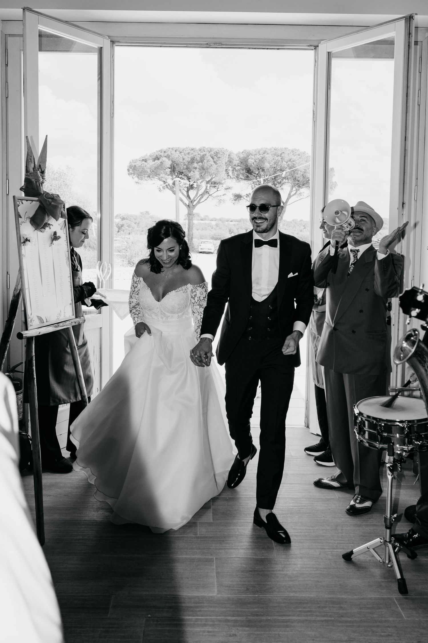 Wedding procession walking through bright indoor corridor in black and white photography.
