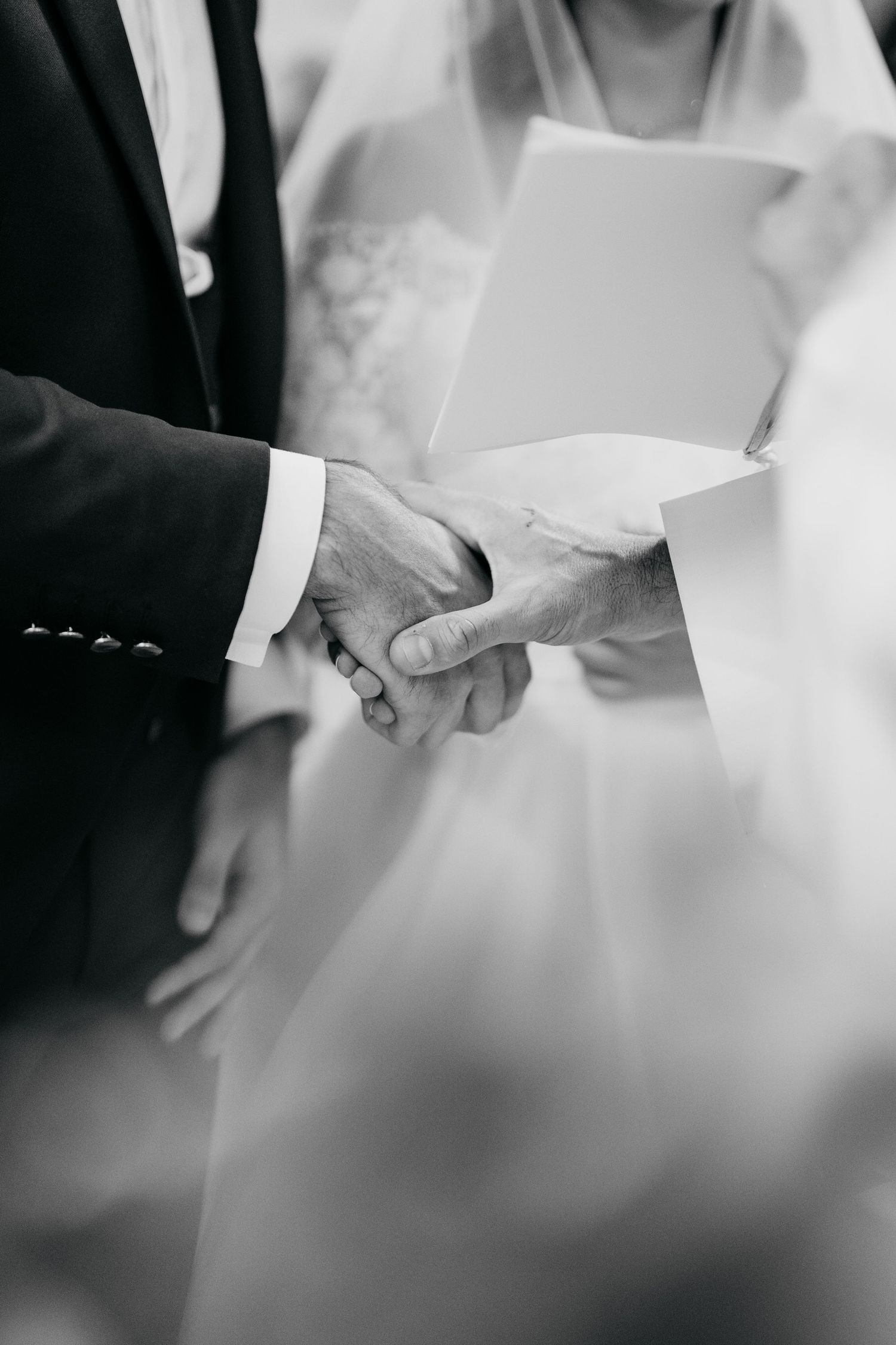 Close-up black and white detail shots of hands holding during a wedding ceremony.
