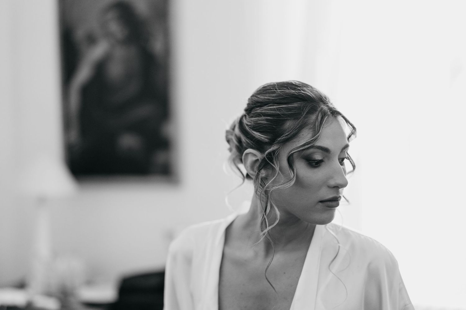 A bride in a white wedding dress getting ready in a black and white photo series.