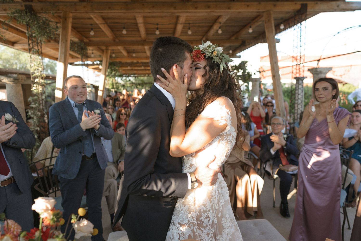 Wedding reception guests enjoying a celebration under a rustic wooden pavilion.