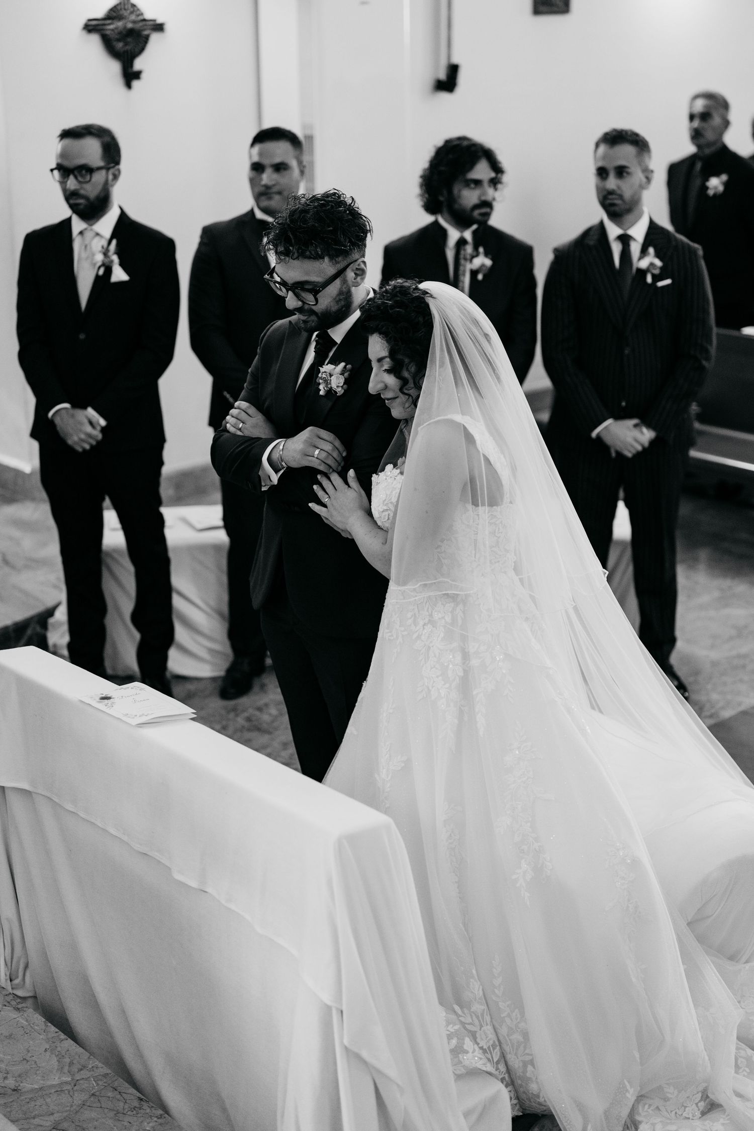 Black and white photo of a bride and groom sharing an emotional moment at the altar during their church wedding ceremony.