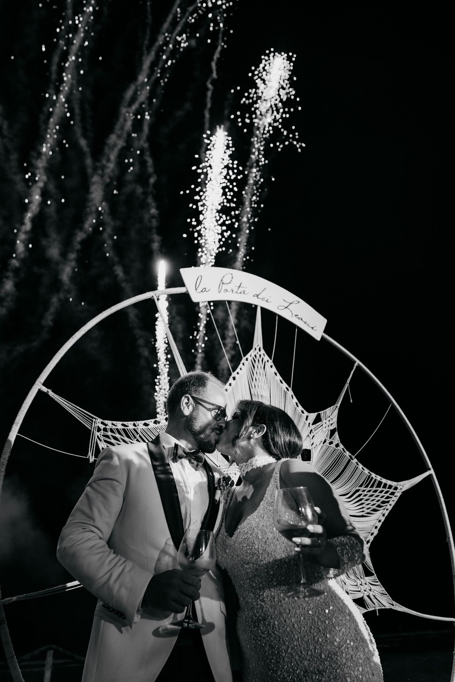 Couple sharing a romantic moment under sparklers and a decorative arch at night.