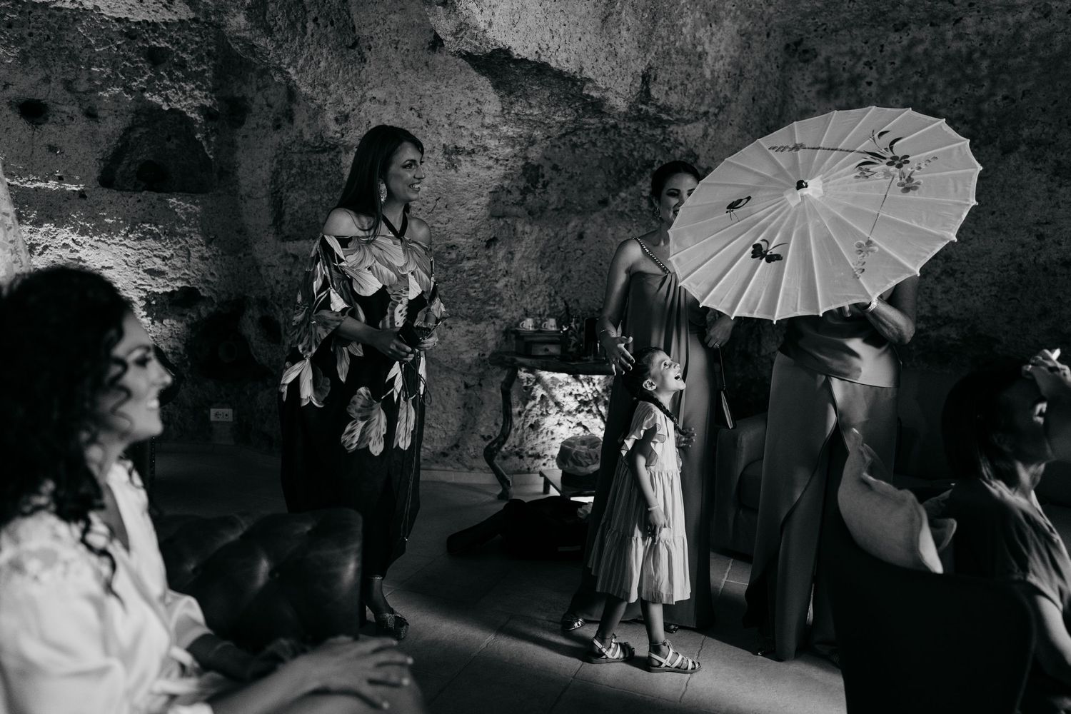 A series of black and white photos showing people holding decorative parasols during what appears to be a wedding celebration.