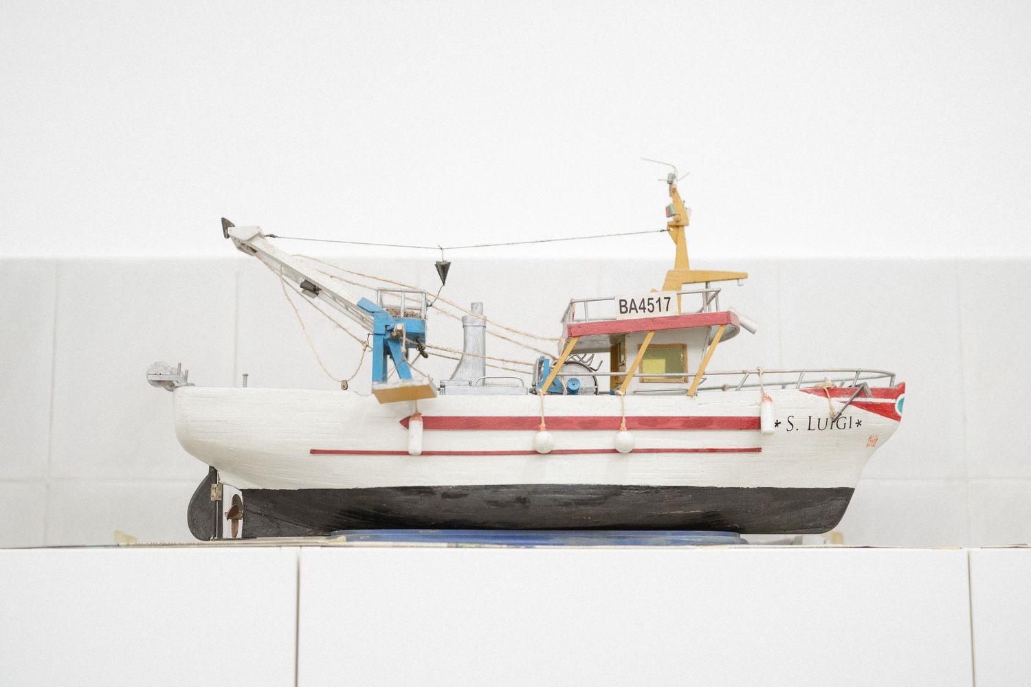 Side view of a white and red fishing boat model with detailed deck equipment and hull markings.