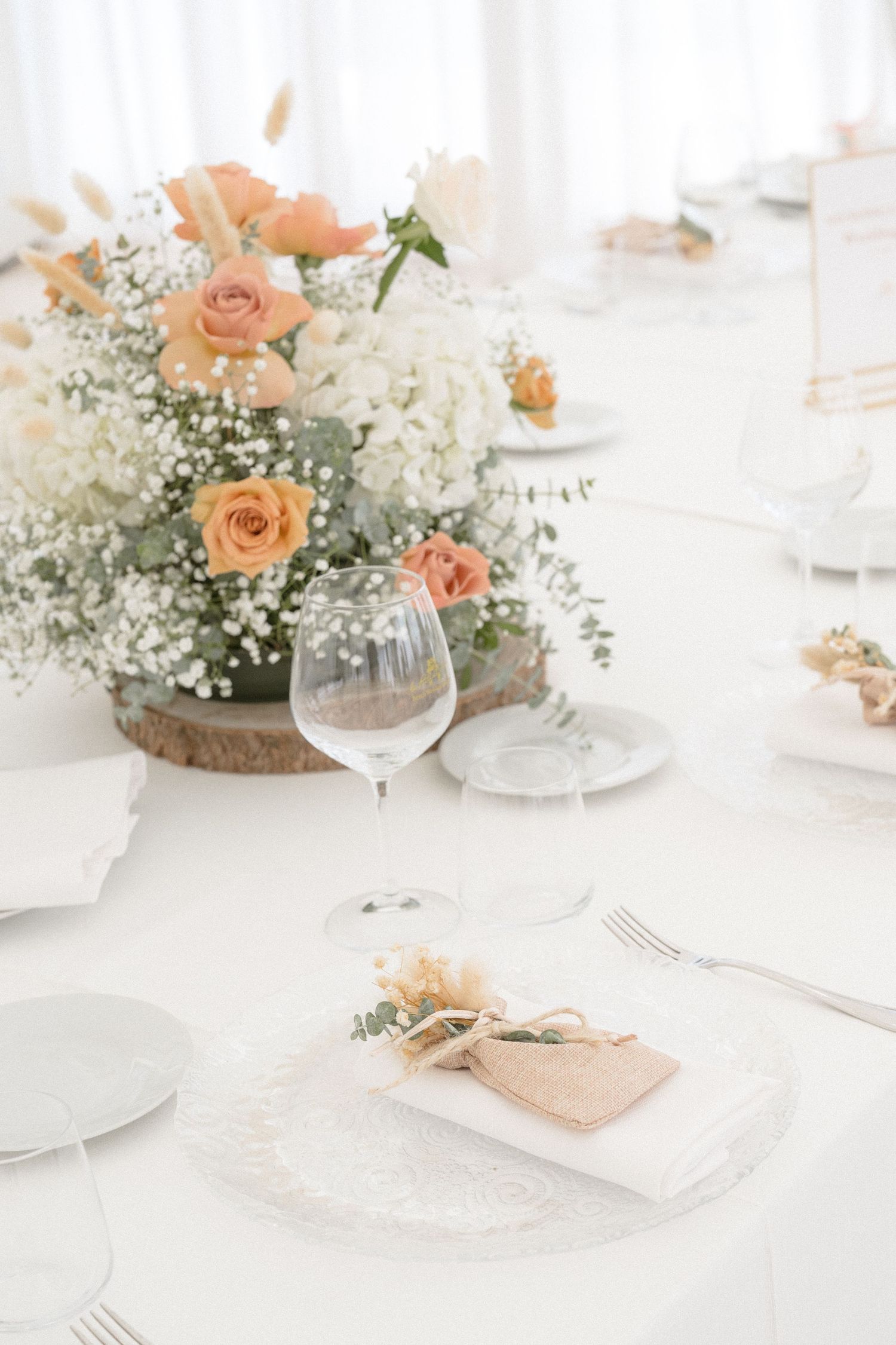 Elegant table setting with peach roses, baby's breath centerpiece and crystal glassware.