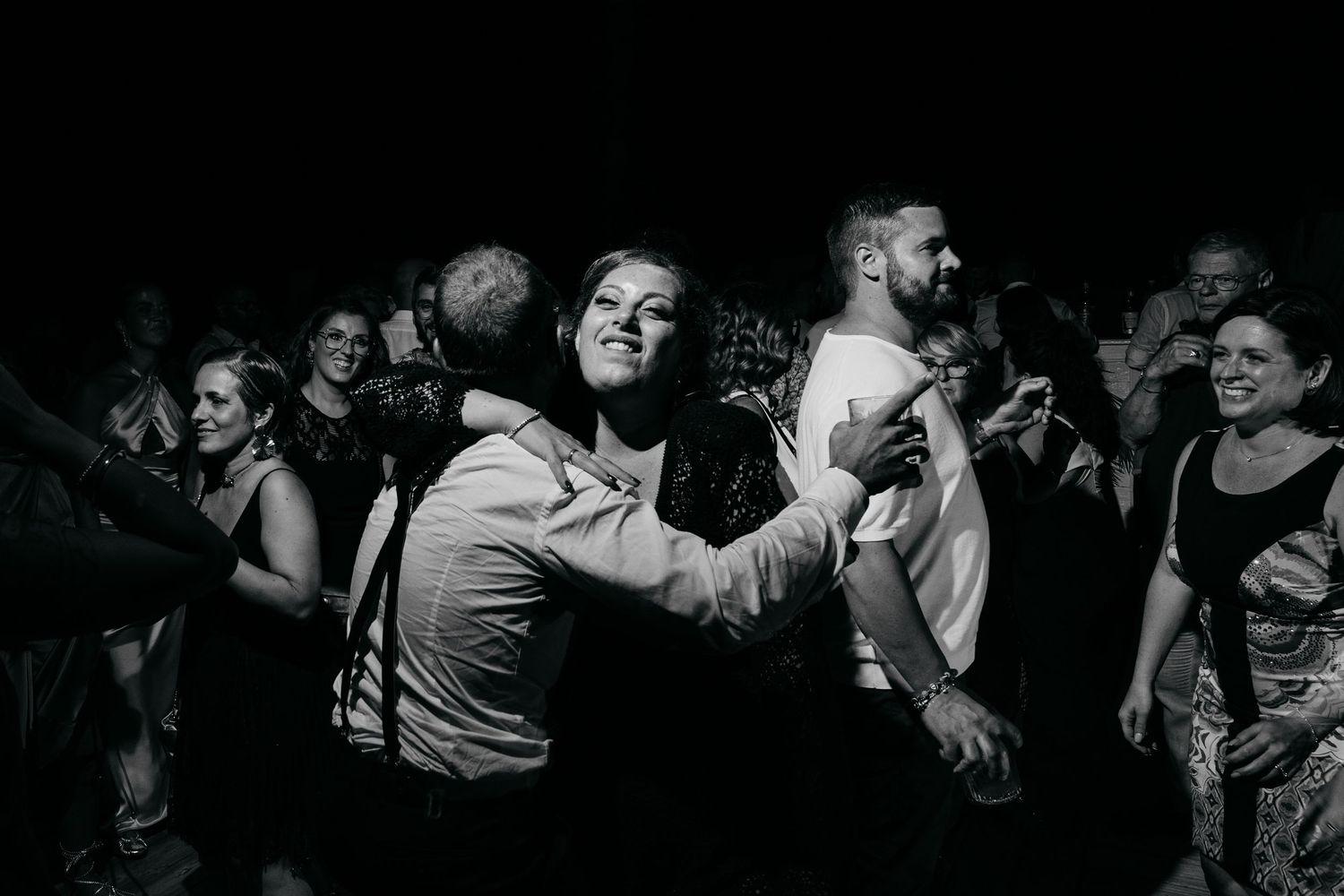 Wedding guests dancing and celebrating on a dark dance floor.